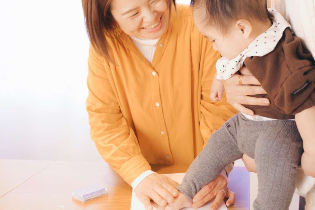 手形アートをする赤ちゃんとベビーマッサージ講師